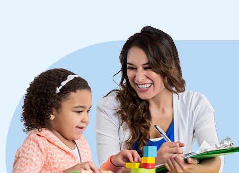 Teacher working with preschool aged girl playing with blocks.