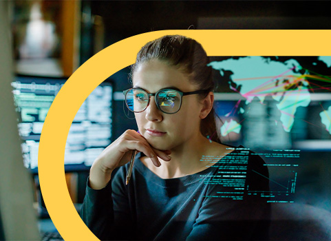 Woman in glasses coding on computer in office.