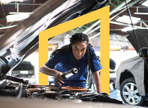 Auto mechanic in blue jumpsuit inspecting car engine.