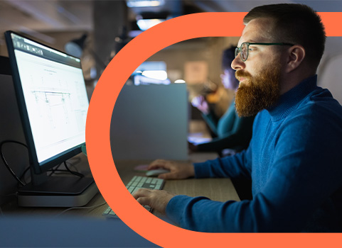 Man with beard and glasses working on computer.