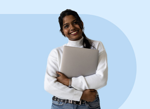 girl in white sweater holding silver laptop.