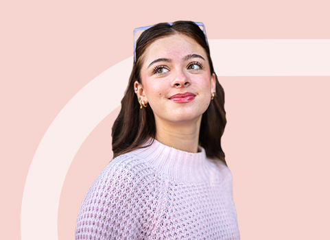 girl with brown hair in white sweater on light red background.