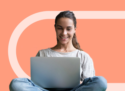 student with silver laptop smiling.