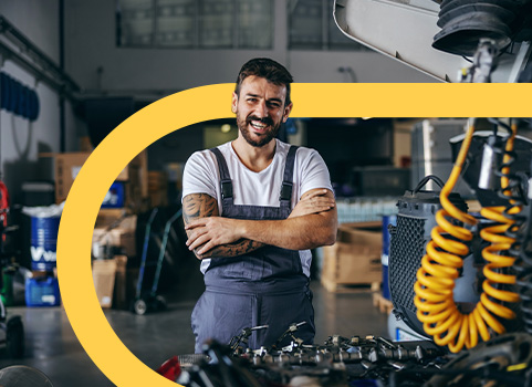 Auto mechanic posing for photo behind vehicle.