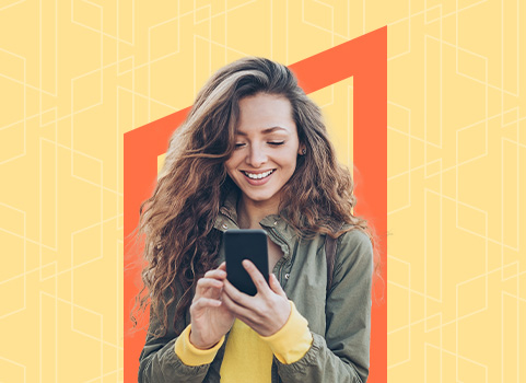 A woman holds a phone and looks at it, smiling